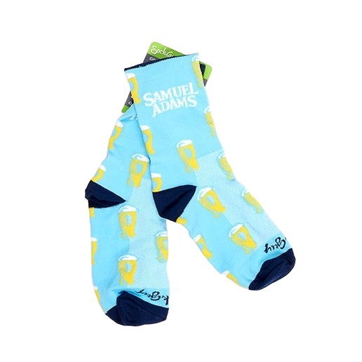 A pair of light blue socks with navy blue around the ankle, heel, and toes, also featuring a design of perfect pints around the whole sock and the Samuel Adams logo above the ankle.