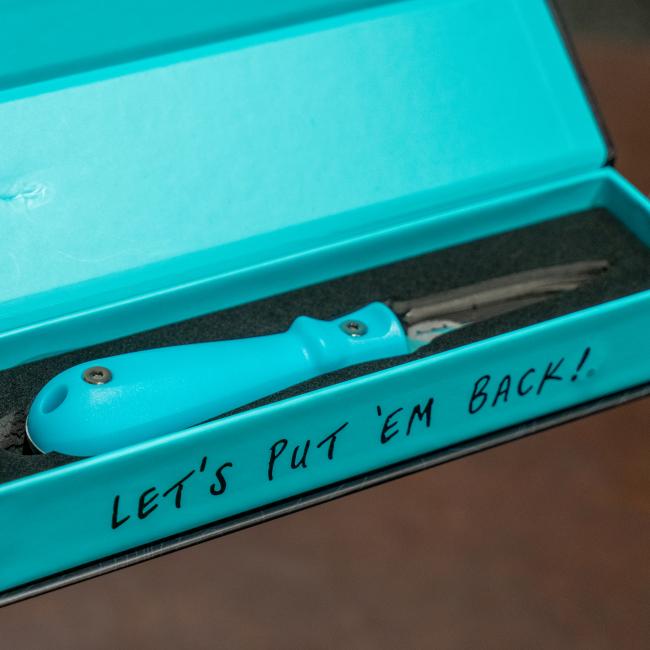Blue oyster knife features the Dogfish Head shark and shield logo engraved on one side of the knife. The other side of the knife features the Toadfish logo engraved.