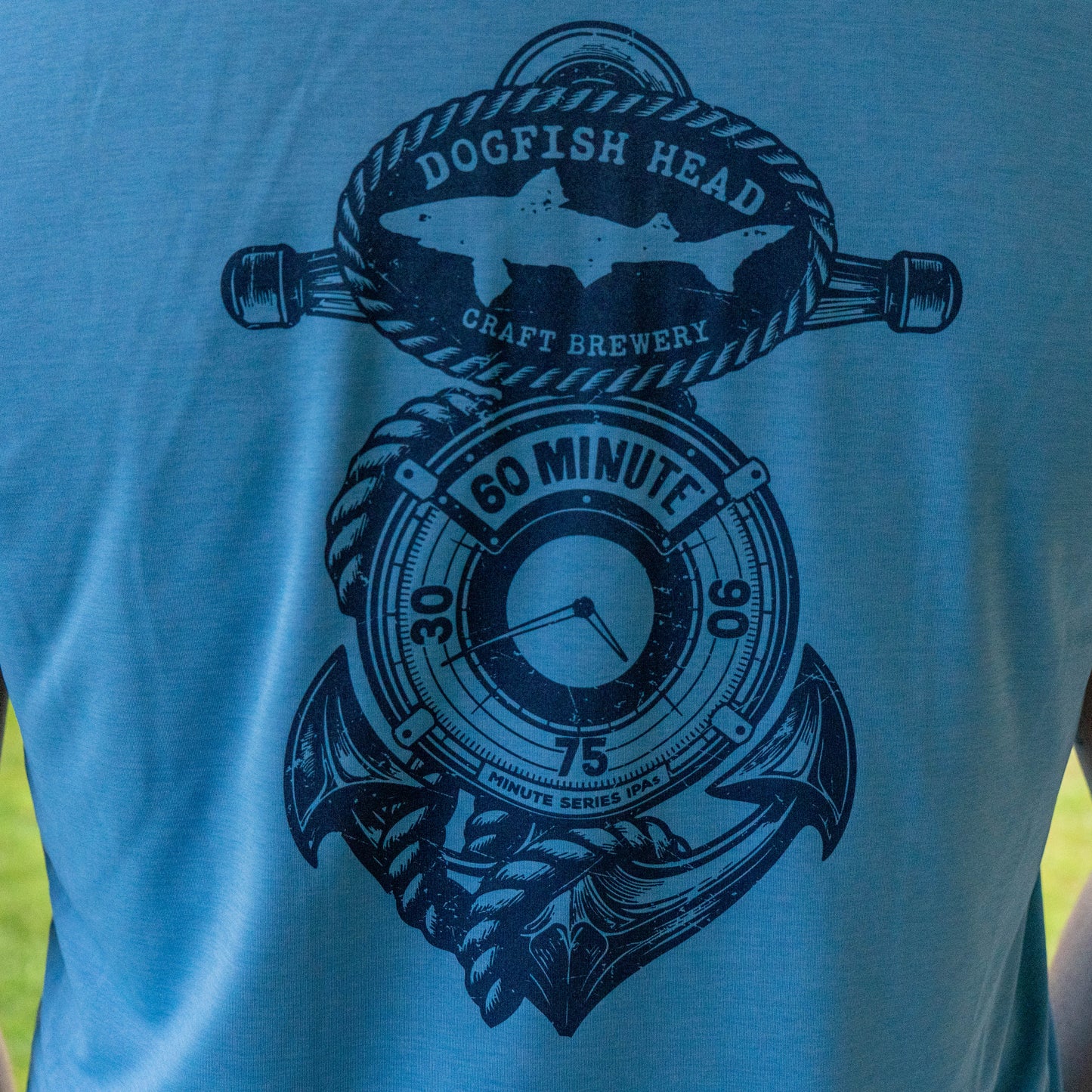 Close-up of Dogfish Head 60 Minute IPA anchor logo on blue Patagonia sleeveless Cap Cool Daily shirt, nautical graphic detail
