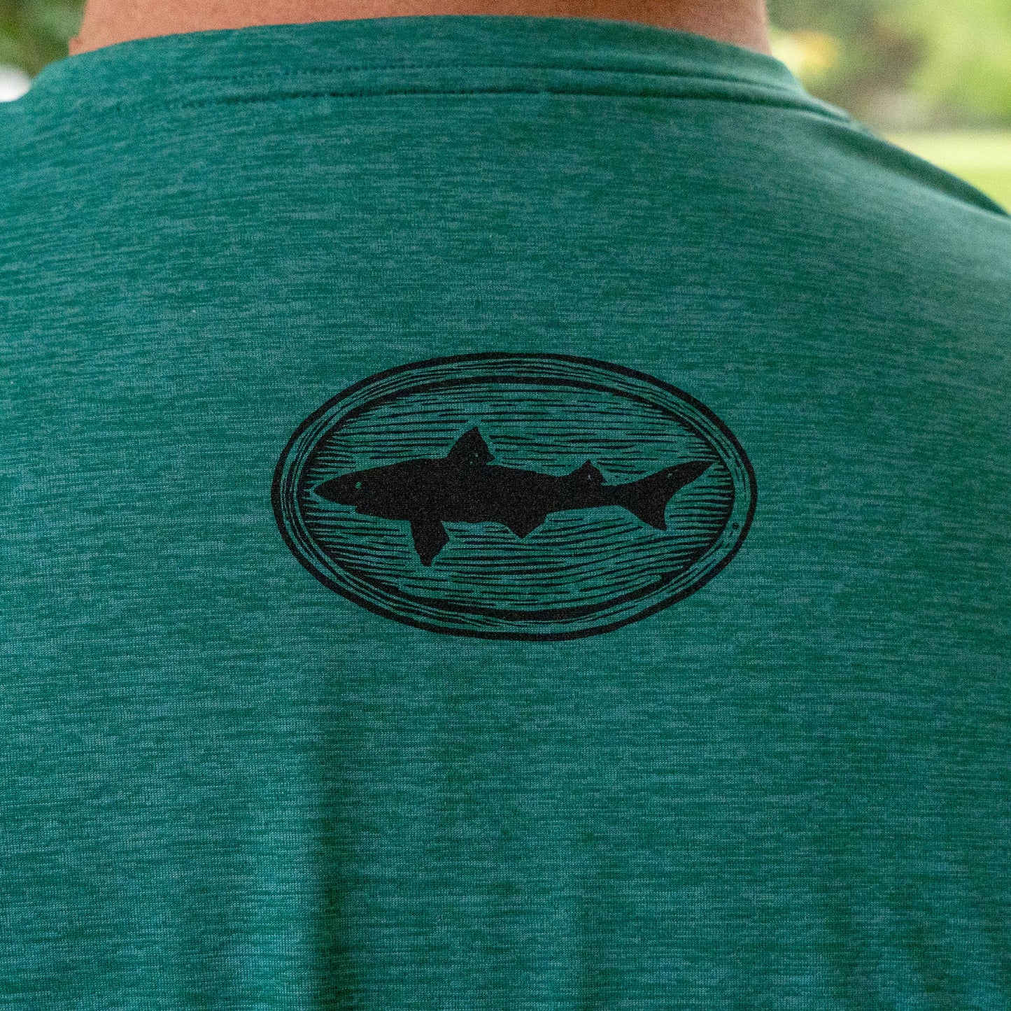 “Close-up of Dogfish Head shark logo on Patagonia Cap Cool Daily Shirt in green, soft heather fabric texture detail