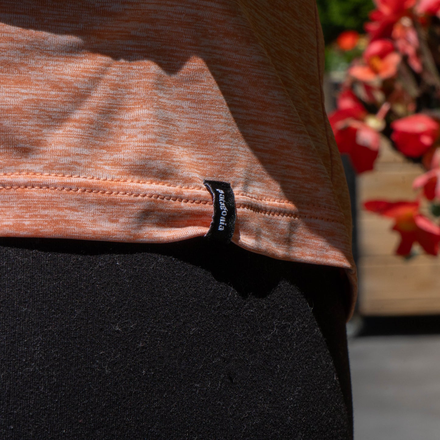 Close up view of bottom hemline on peach patagonia shirt, showing a patagonia branded tag