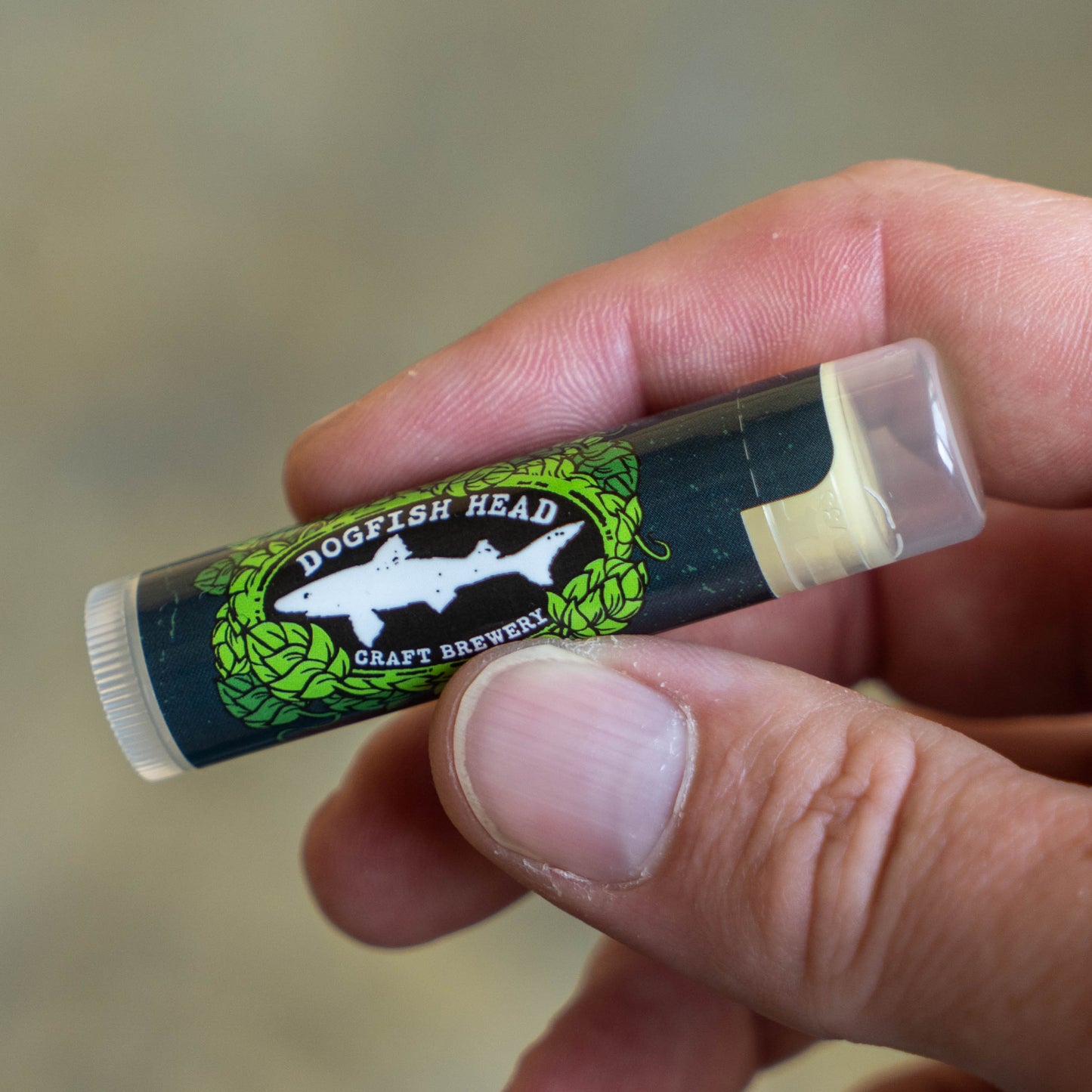 A close-up of a person holding a tube of Vanilla Lip Balm with a label reading Ecolips, featuring subtle leaf designs and clean, natural branding.