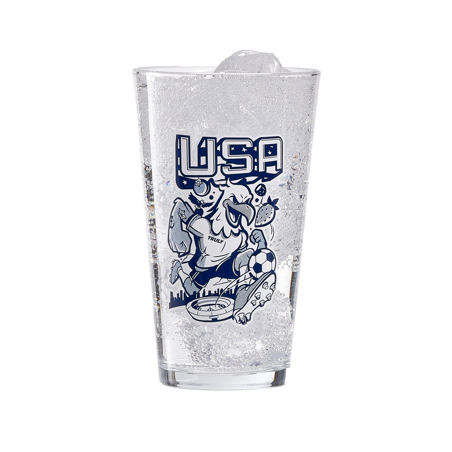 Clear pint glass filled with ice and a fizzy beverage, displaying a navy illustration with large “USA” text above a stylized eagle character graphic and decorative fruit elements. The design sits prominently on the front of the glass, creating a bold, eye‑catching barware piece.