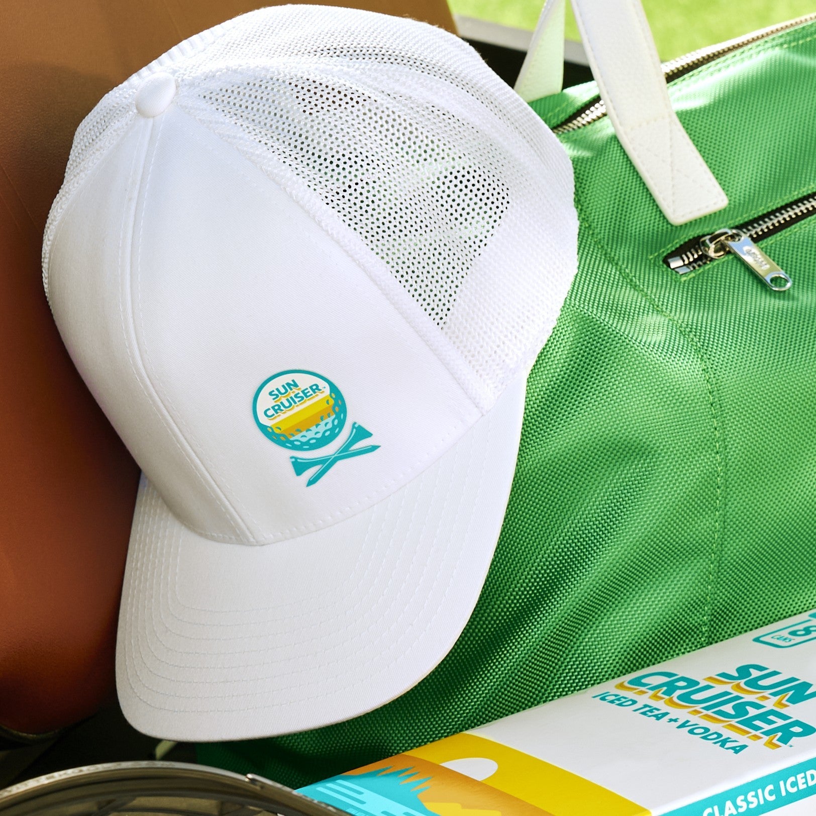 White Sun Cruiser x GFore golf hat sitting on a green Sun Cruiser x GFore shoe bag