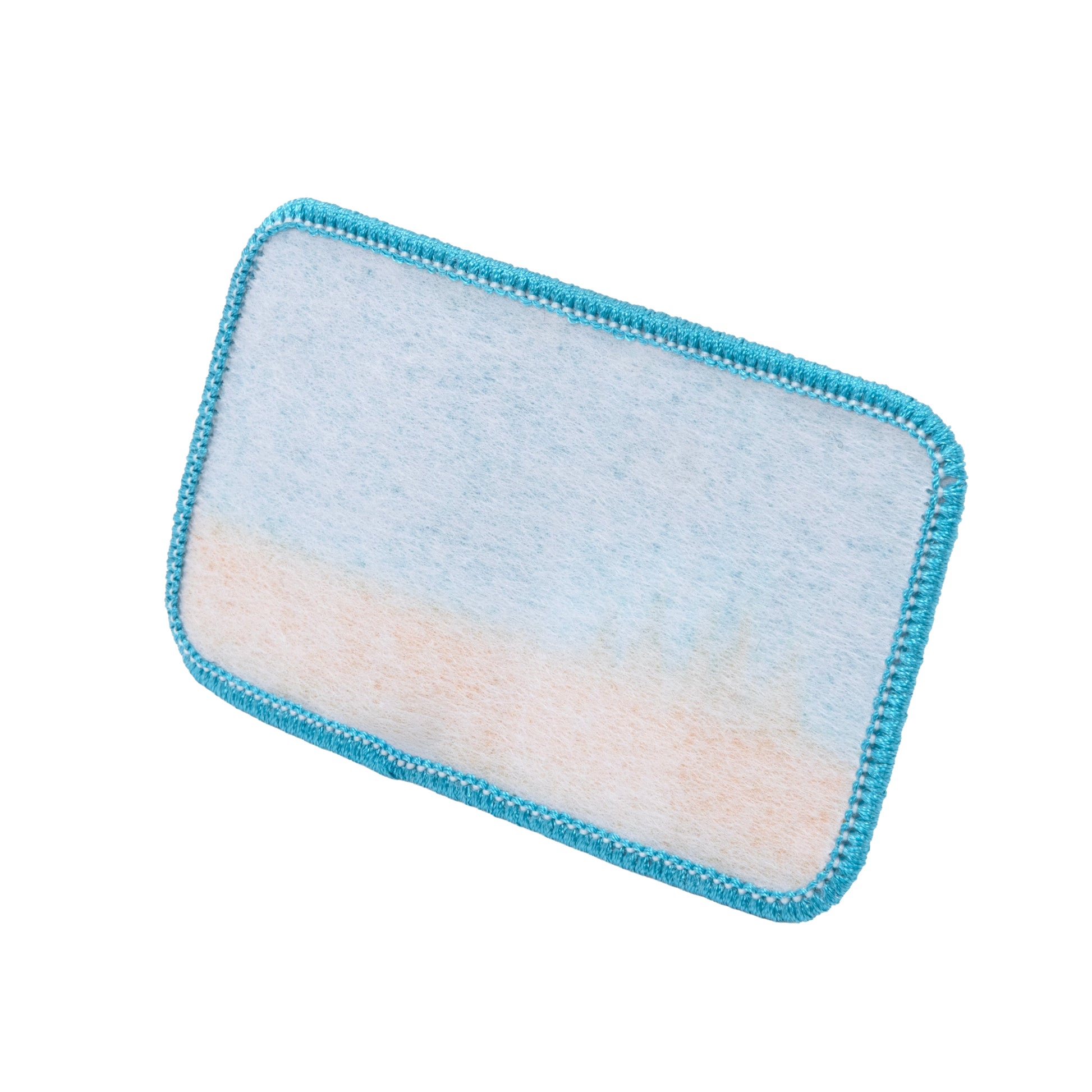 Back side of Sun Cruiser patch showing heat-activated adhesive backing with stitched turquoise border for easy application