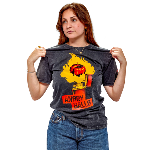 Shown by a person wearing it, this washed black tee features a red lighter with a yellow flame being released. In the flame is a red apple, and under the lighter is writing "Angry Balls". On the left arm is the writing "Angry Orchard x Fireball".