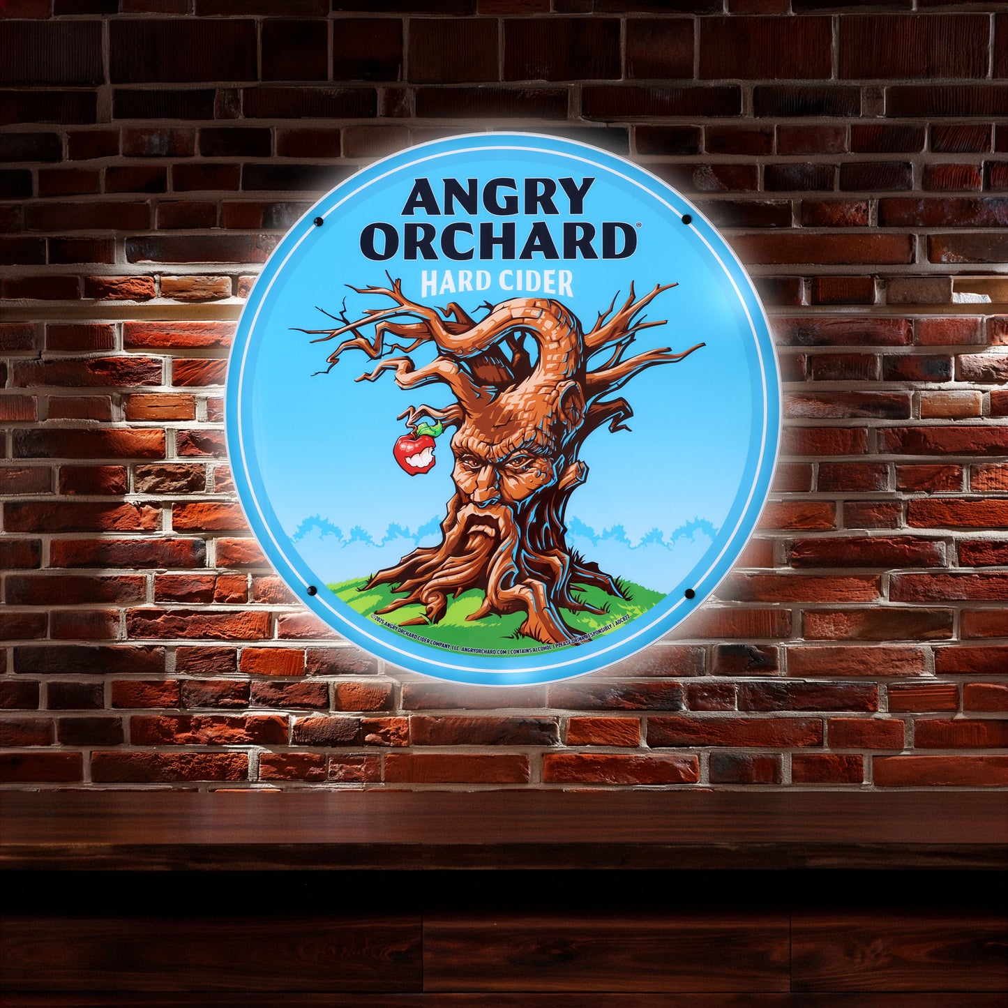 Angry Orchard hard cider logo on a circular sign against a brick wall.