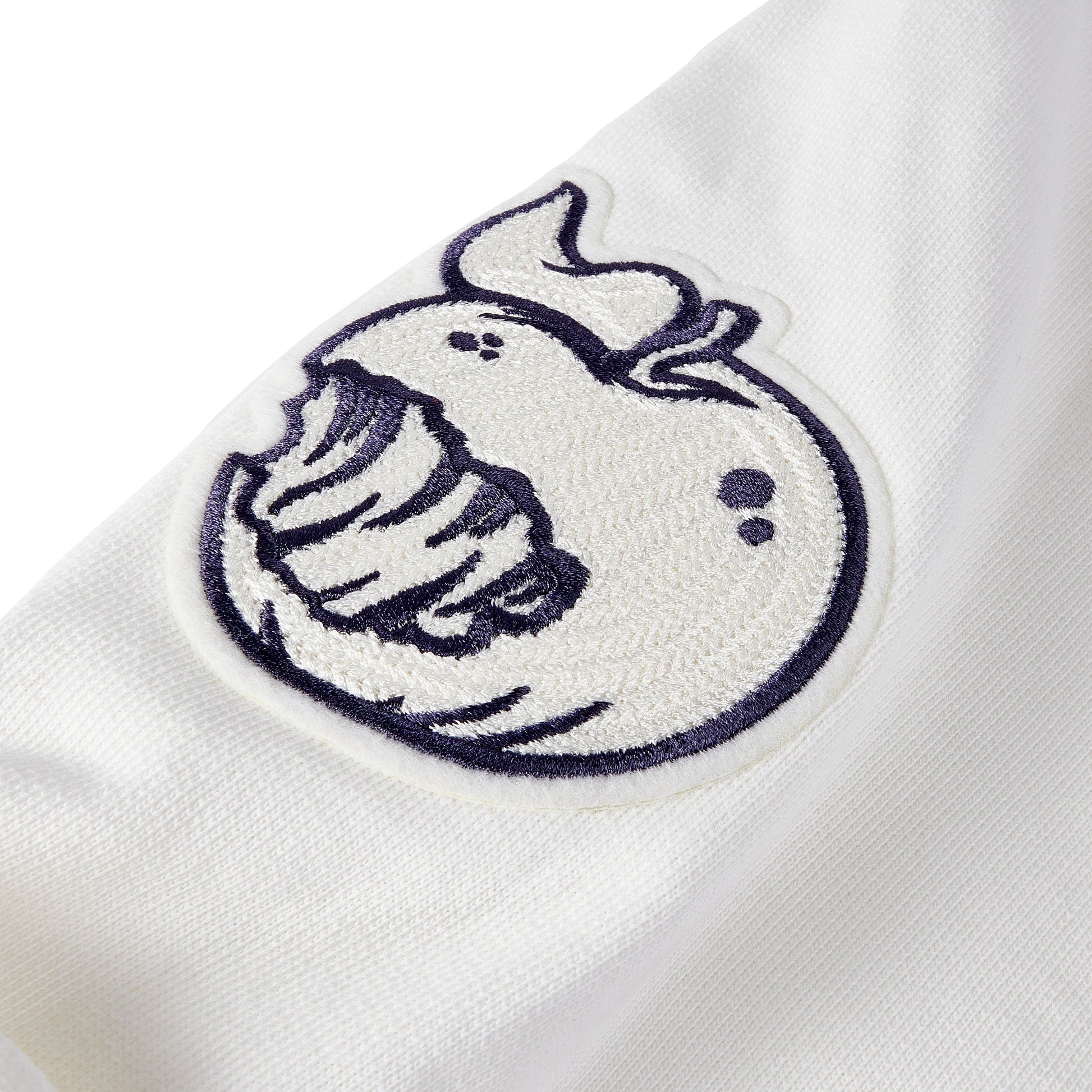 Detail shot of the Angry Orchard White Walden Crew Sweatshirt sleeve embroidery of an Angry Orchard Apple 