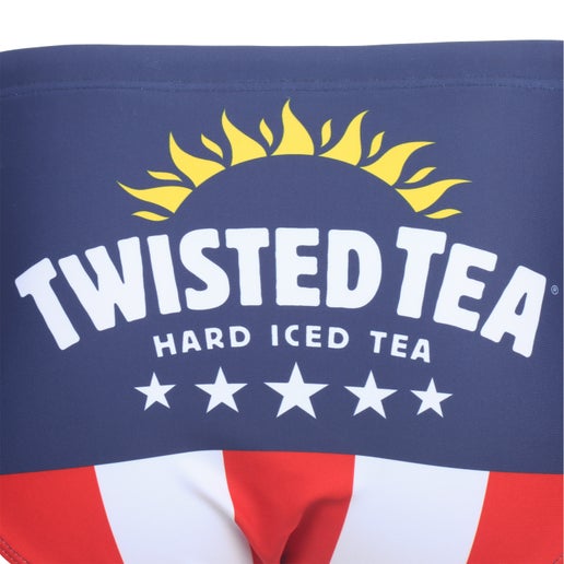 Close-up of the front of men's swim briefs, showing the upper dark blue section with "TWISTED TEA HARD ICED TEA" in white text, a golden sunburst design above it, and five white stars below. Below this section are vertical red and white stripes.