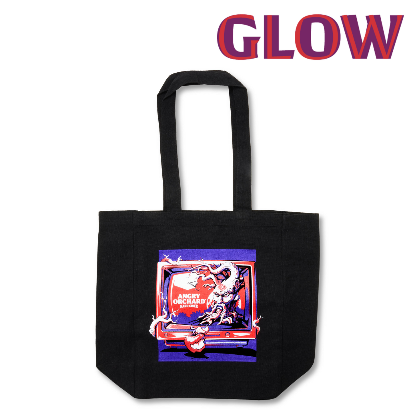 A black canvas tote bag with a colorful graphic print on the front, featuring a retro television design with the words 'ANGRY ORCHARD' and 'HARD CIDER'. The word 'GLOW' is printed in large red and purple letters at the top of the image.