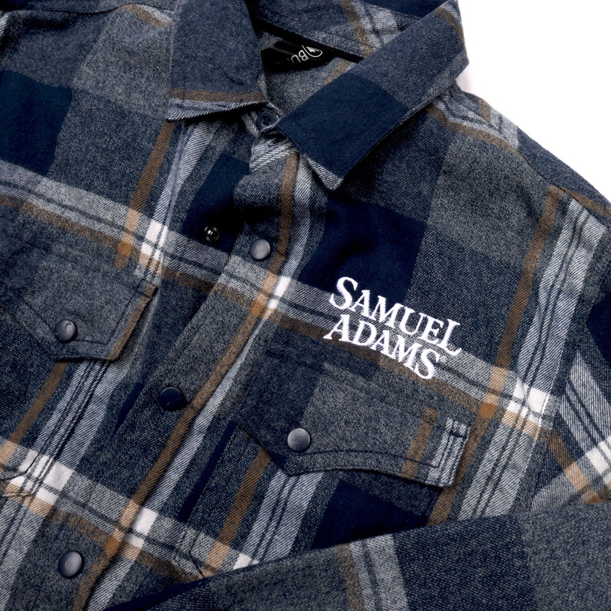 Blue flannel with a white Samuel Adams logo written on the left side of the chest above the pocket.