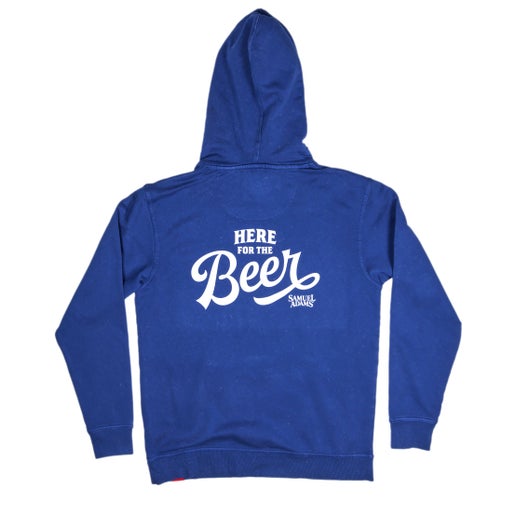 Front and back view of a blue Samuel Adams hoodie. The front features a small white Samuel Adams shield logo on the left chest; the back displays a bold white "Here for the Beer" graphic with the Samuel Adams logo underneath.