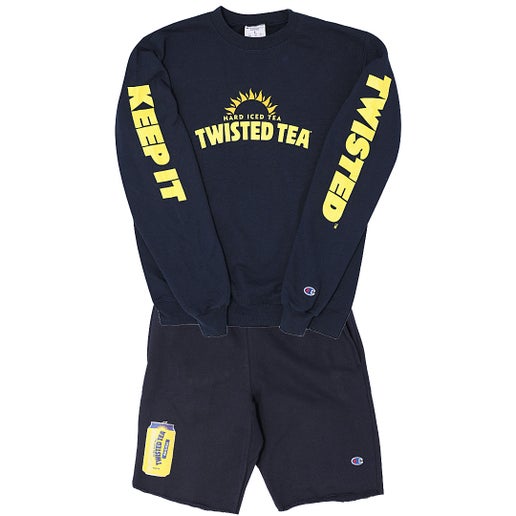 A matching dark blue Champion loungewear set, featuring a crewneck sweatshirt and shorts, displayed against a white background. The sweatshirt has yellow "TWISTED TEA HARD ICED TEA" branding with a sunburst on the chest, and "KEEP IT" vertically in yellow on the left sleeve and "TWISTED" vertically in yellow on the right sleeve. The shorts feature a yellow Twisted Tea can graphic on the lower left leg. Both garments have small Champion logos visible.