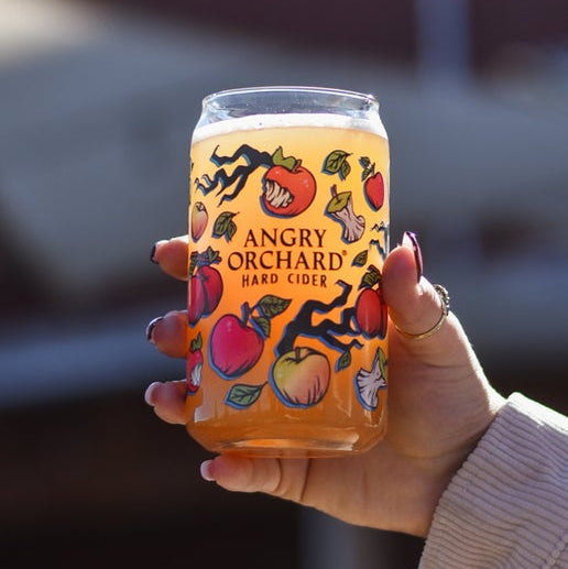 This can glass is covered in small images of branches, leaves, whole apples, and bitten apples. These small images surround the writing "Angry Orchard Hard Cider".