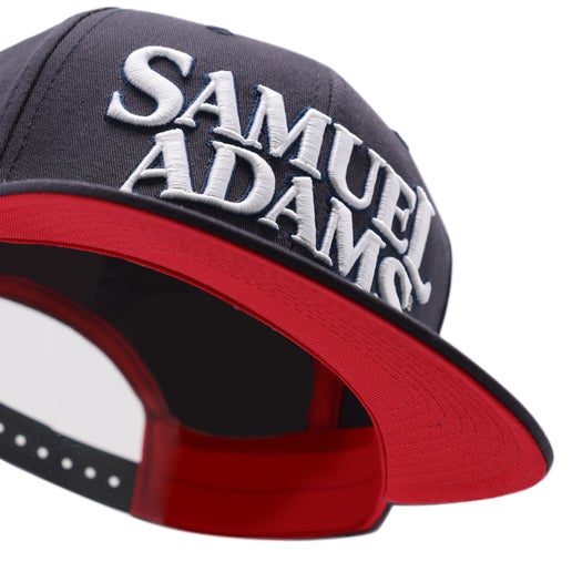 Hat features an adjustable back, navy blue exterior, red interior, and thick, risen Samuel Adams embroidery in white.