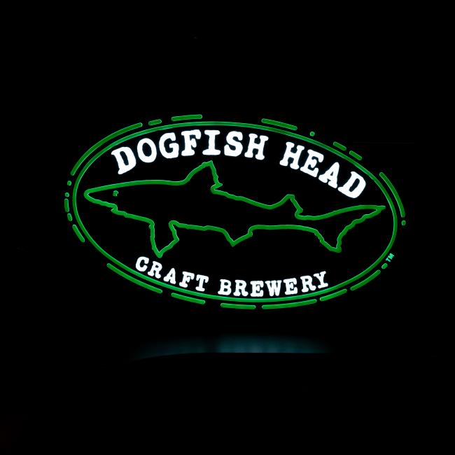 The Merchtank Craft Brewery Logo LED Neon features a green shark outline and white "DOGFISH HEAD CRAFT BREWERY" text inside a green oval border on a black background.