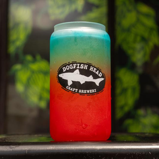 A vibrant Ombre Color Changing Can Glass by Grandstand Glassware & Apparel displays a striking red-to-blue gradient, set against leafy green for a bold visual statement.