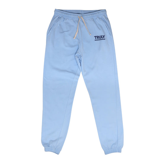 A pair of light blue sweatpants with elastic cuffs and a beige drawstring waistband. The word "TRULY" is printed in dark blue with an underline on the upper left thigh.