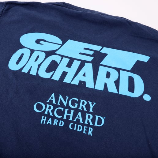 Close-up of writing on back of tee. Features writing "Get Orchard." and "Angry Orchard Hard Cider" below it in light blue.
