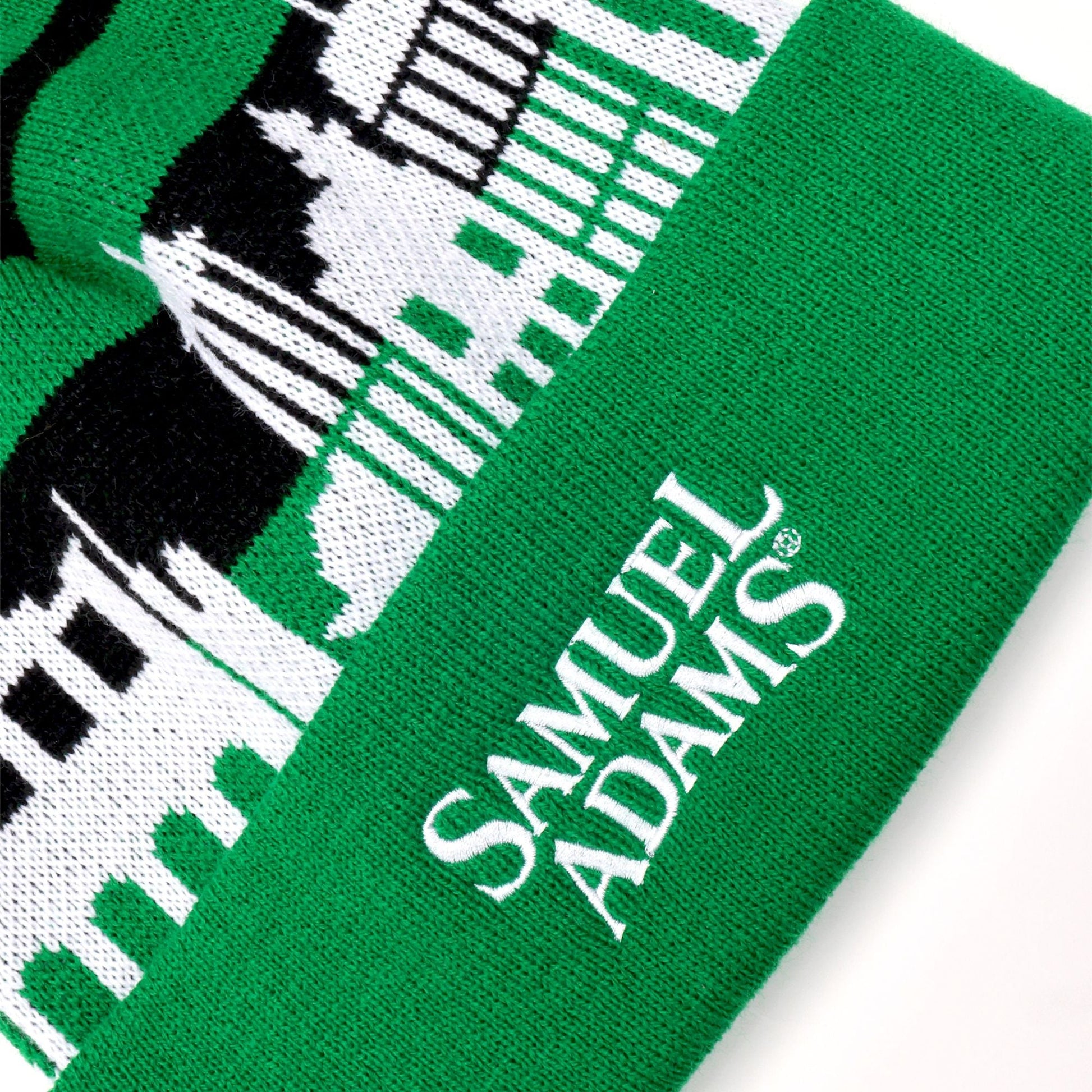 Green beanie with black horizontal stripe and white Boston Skyline. White Samuel Adams text