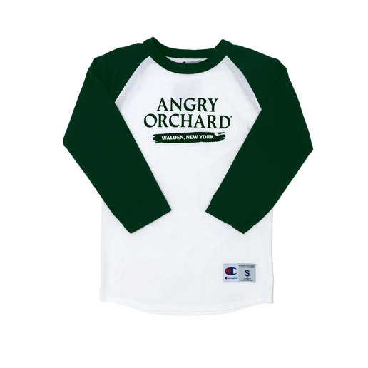 This baseball tee has a white base and green sleeves. The front of the tee displays writing "Angry Orchard" and "Walden, New York" directly under. Champion logo is displayed on bottom of left sleeve and bottom left of tee. 