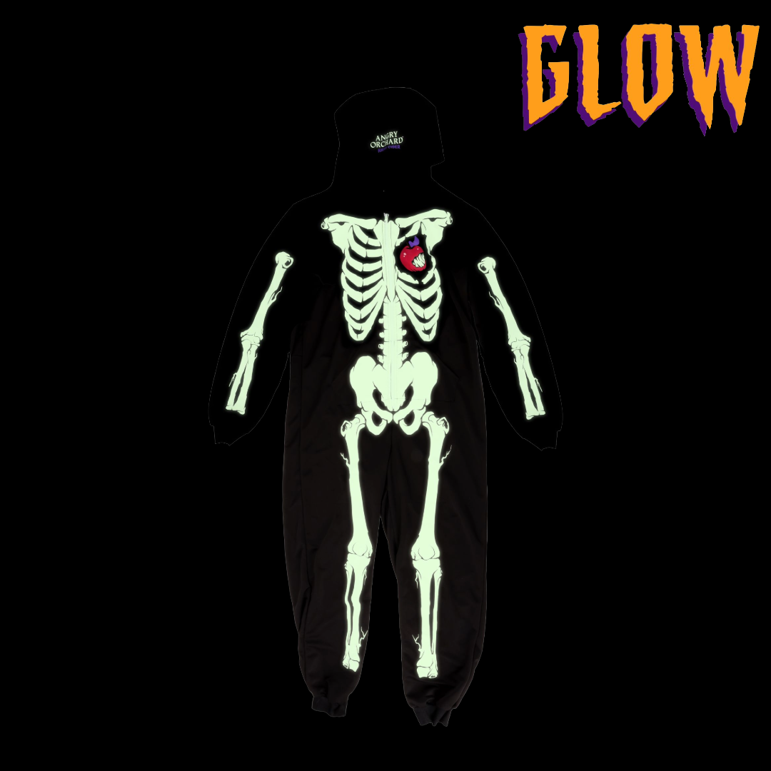 Black onesie with full skeleton on the front with the iconic Angry Orchard bitten red apple in place of a heart. GLOW text describing glow in the dark feature of skeleton bones.