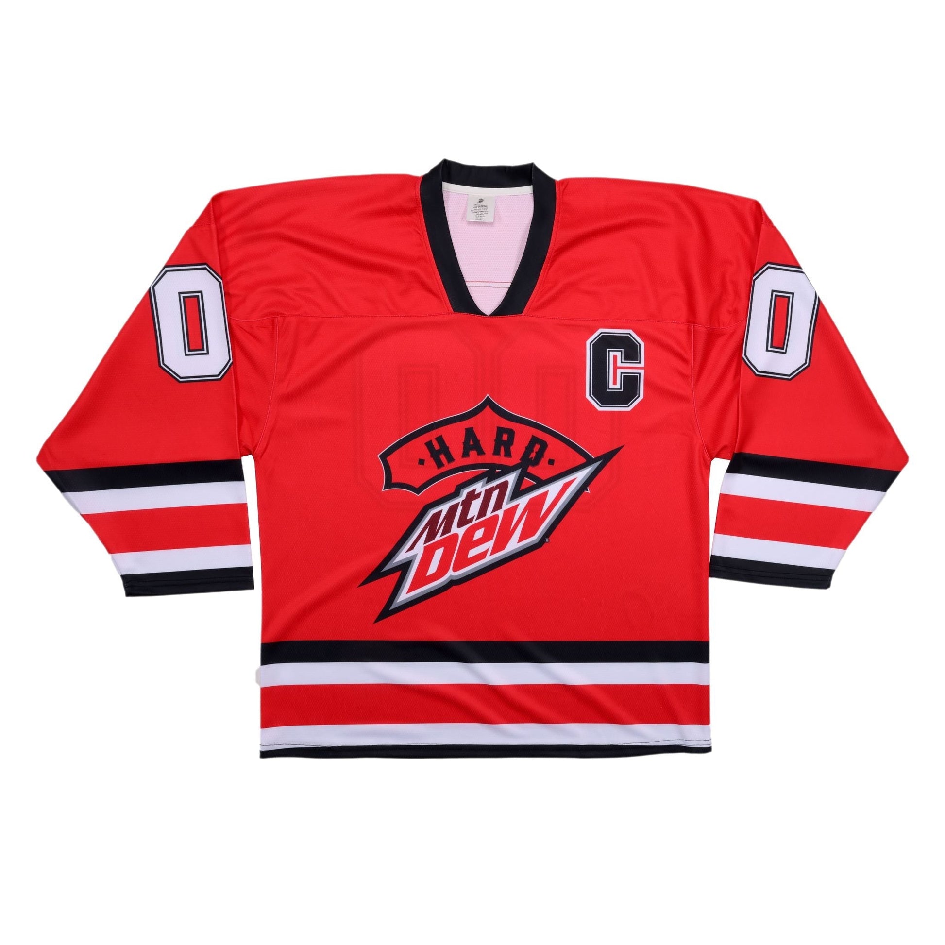 A vibrant red hockey jersey displayed flat, featuring a black V-neck collar. The front displays the 'Hard Mtn Dew' logo prominently in the center, with 'Hard' on a red banner above the white, red, and black Mtn Dew logo. A black 'C' is on the upper right chest, and the number '0' in white with a black outline is on both shoulders. Black and white stripes adorn the forearms.