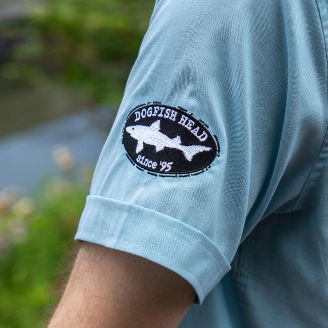 Close up of the embroidered Dogfish Head shark and shield logo featured on the bottom of the right sleeve.