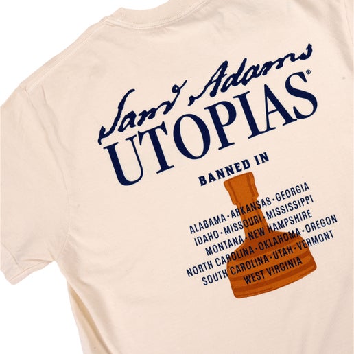 Close-up of the back graphic displaying the bold Utopias logo, copper bottle, and banned state list in navy and orange ink.
