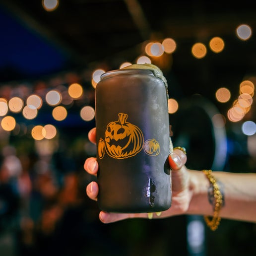 Color changing can glass features imagery of orange pumpkin on the front with a smaller one on both sides of the larger.