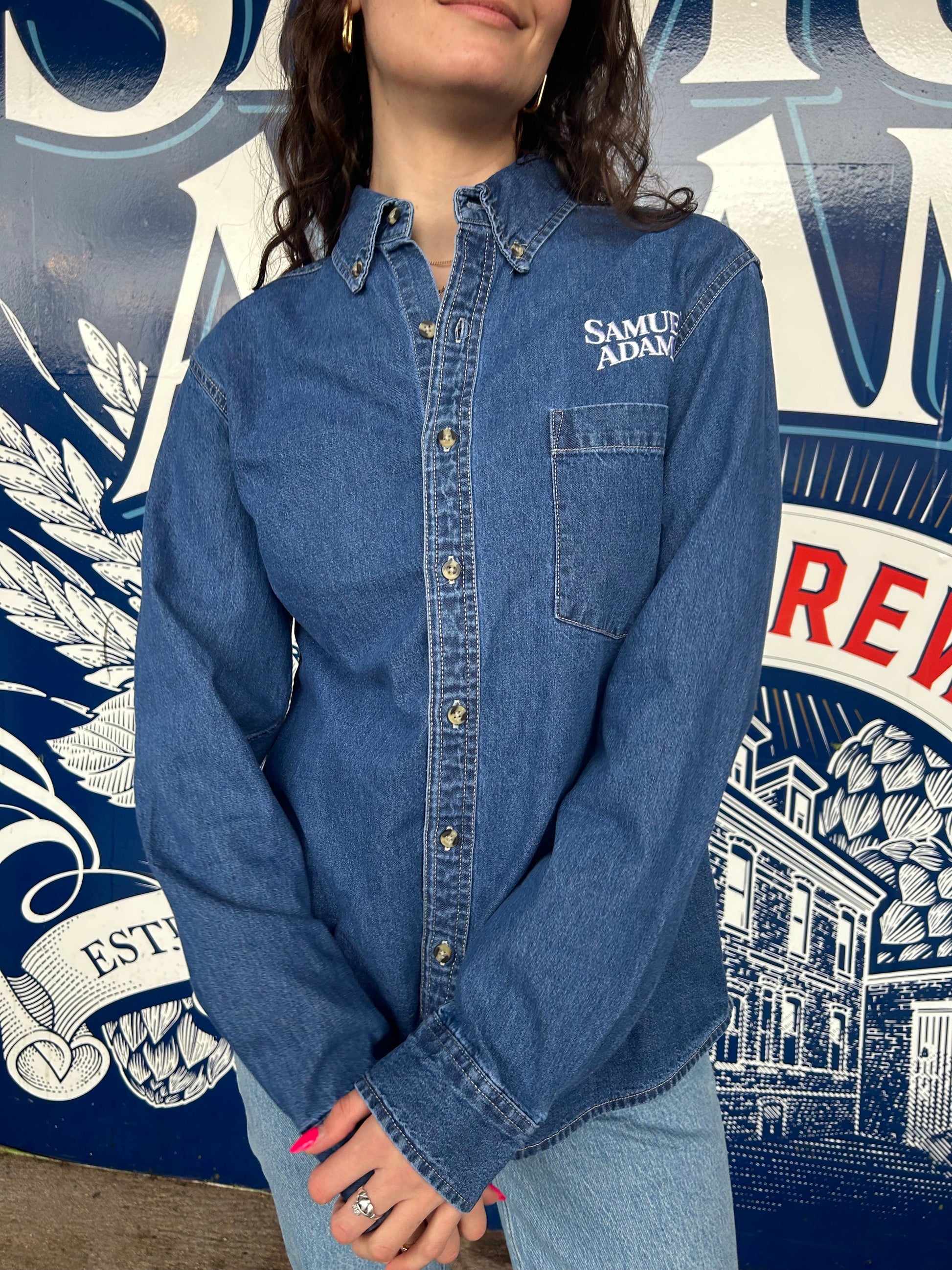 Jim Koch-inspired Jean/denim Button Up Shirt embroidered with the Samuel Adams classic logo over a pocket on the left side of the chest.