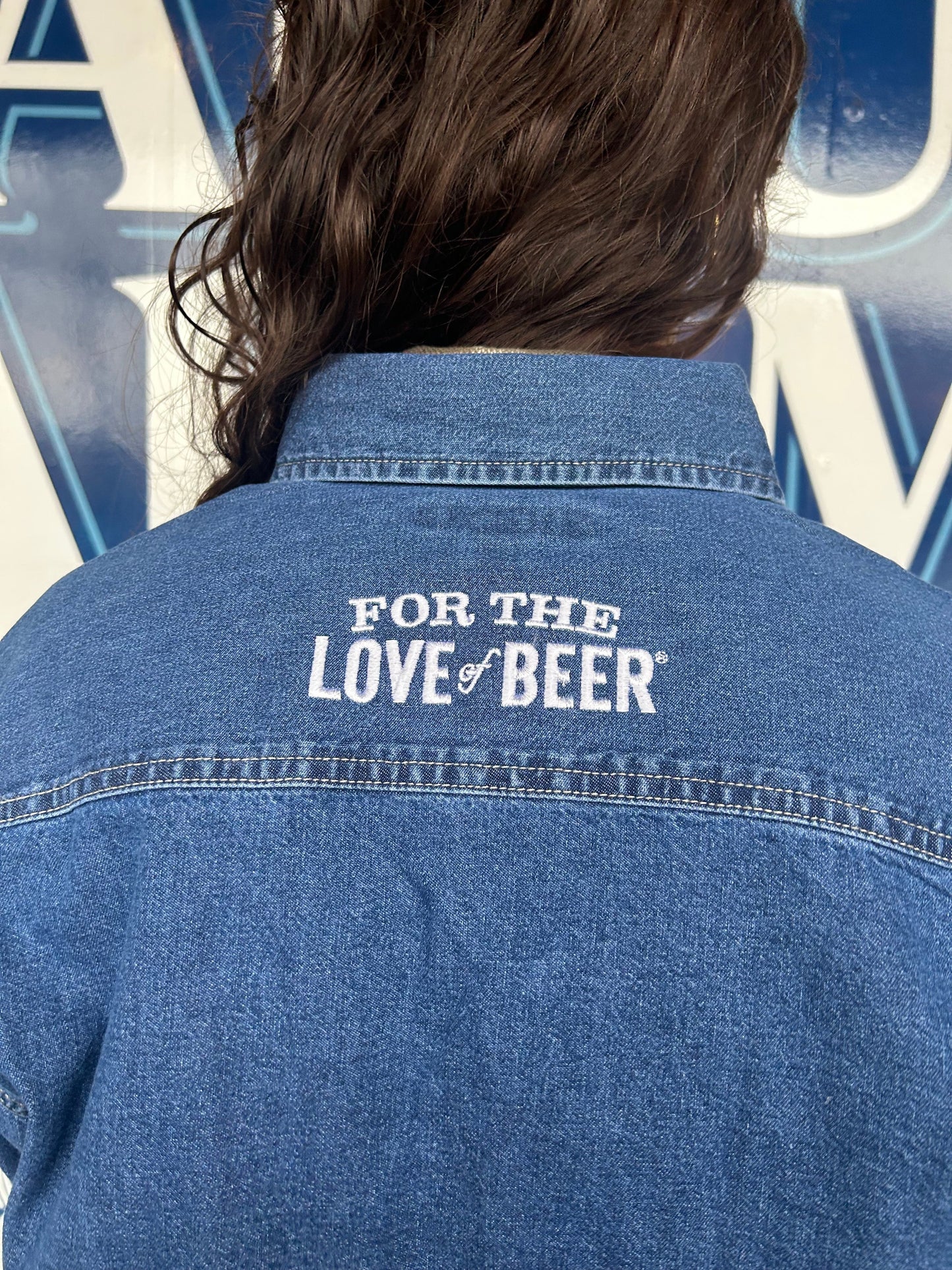 Back of the jean button up shirt is embroidered on the upper back with the slogan "For the love of beer"