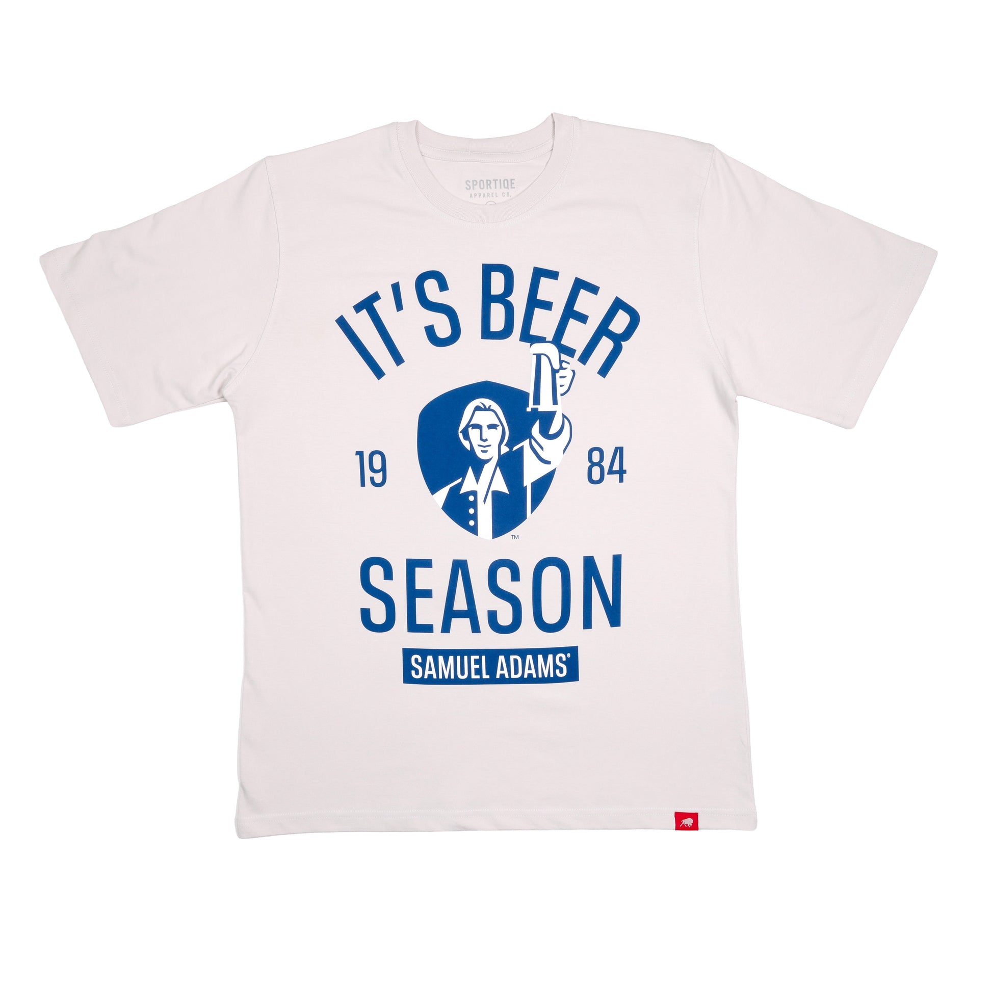 Front view of gray tee features blue writing "It's Beer Season", "Samuel Adams", "1984", and imagery of Sam Adams hoisting a stein on a blue shield background.