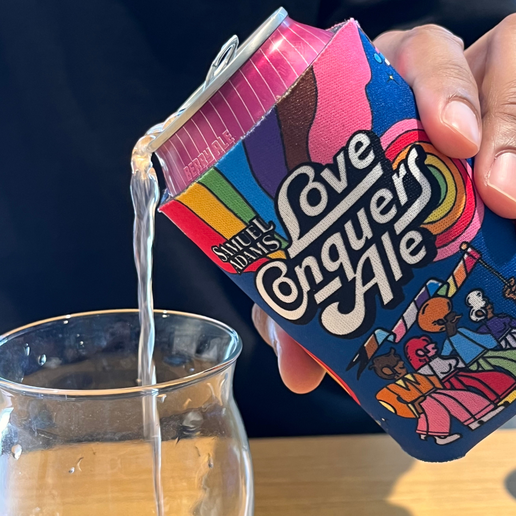 Love Conquers Ale can cooler on a Samuel Adams berry ale being poured into a pint glass