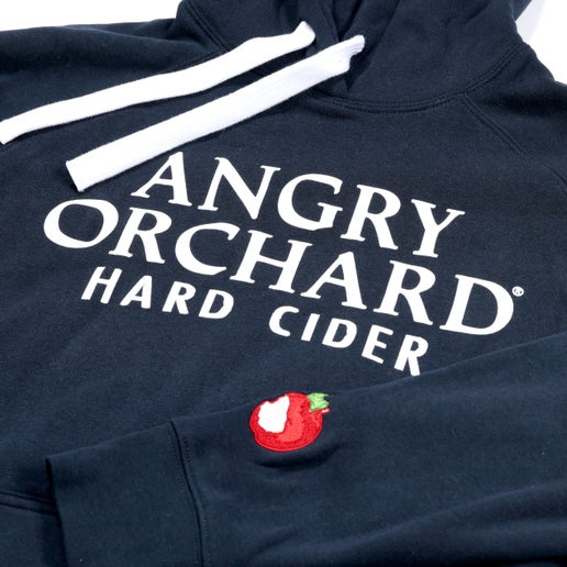 Front of navy hoodie features centered writing "Angry Orchard Hard Cider" in white. On left sleeve by wrist is the Angry Orchard red bitten apple logo. 