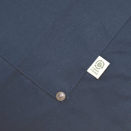 A close up view of the silver studs on each corner of the apron front pocket and the tag that reads "Organic recycled"