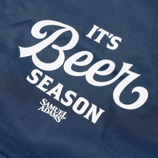 A navy apron with a large front pocket under a slogan that reads "It's Beer Season"