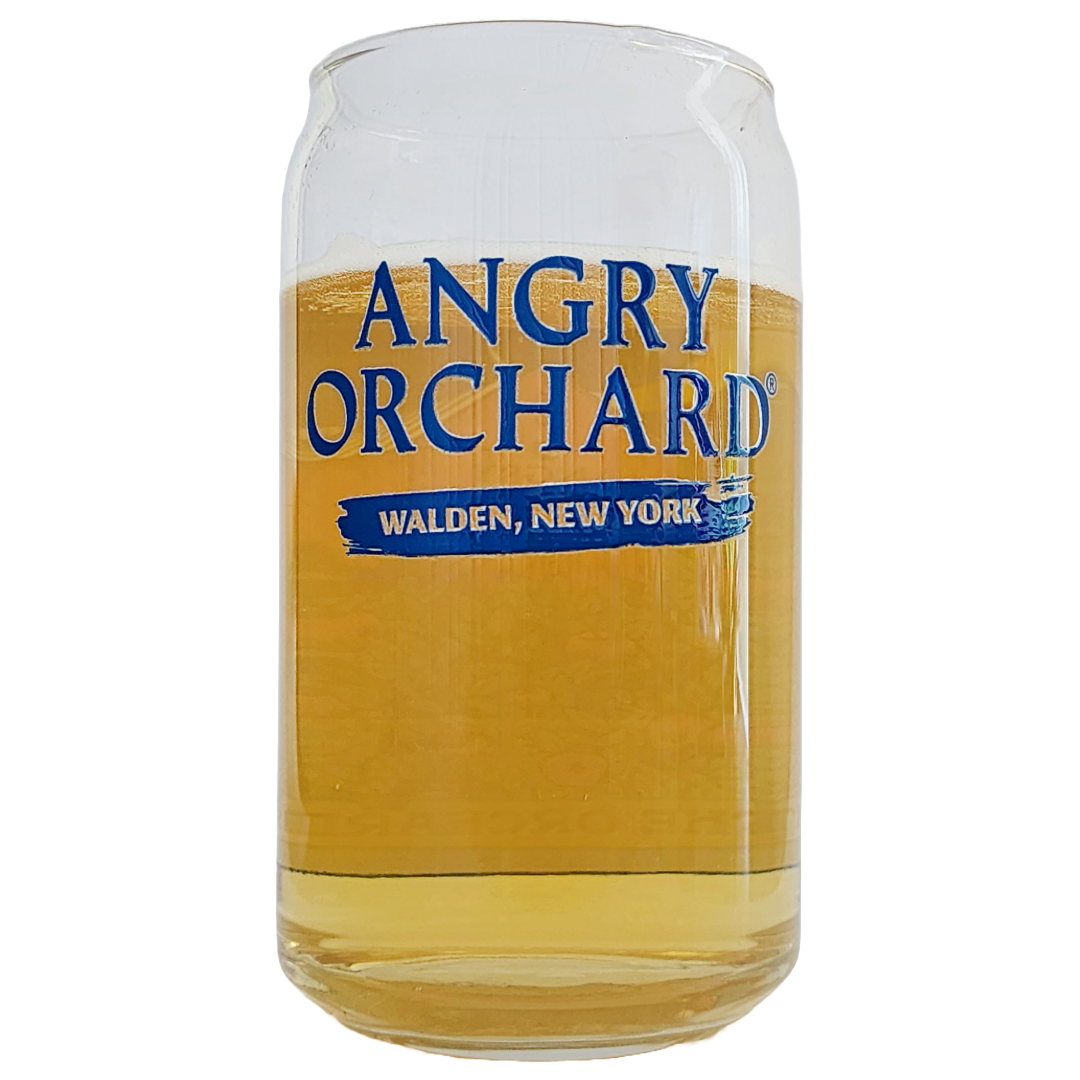 Clear Angry Orchard pint glass filled with hazy golden hard cider, light amber tones glowing through the glass. Bold navy-blue Angry Orchard logo and the words Walden, New York are printed on the front
