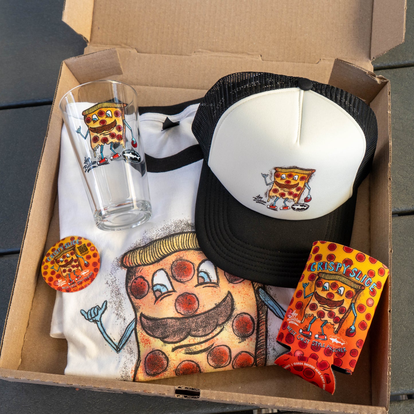 The Crispy Slice Merch Bundle from GO WEST T-SHIRT COMPANY includes a t-shirt, glass, hat, pin, and drink koozie—each featuring a cartoon pizza slice with arms, legs, mustache, sunglasses, and "Krispy Slice" on the koozie.