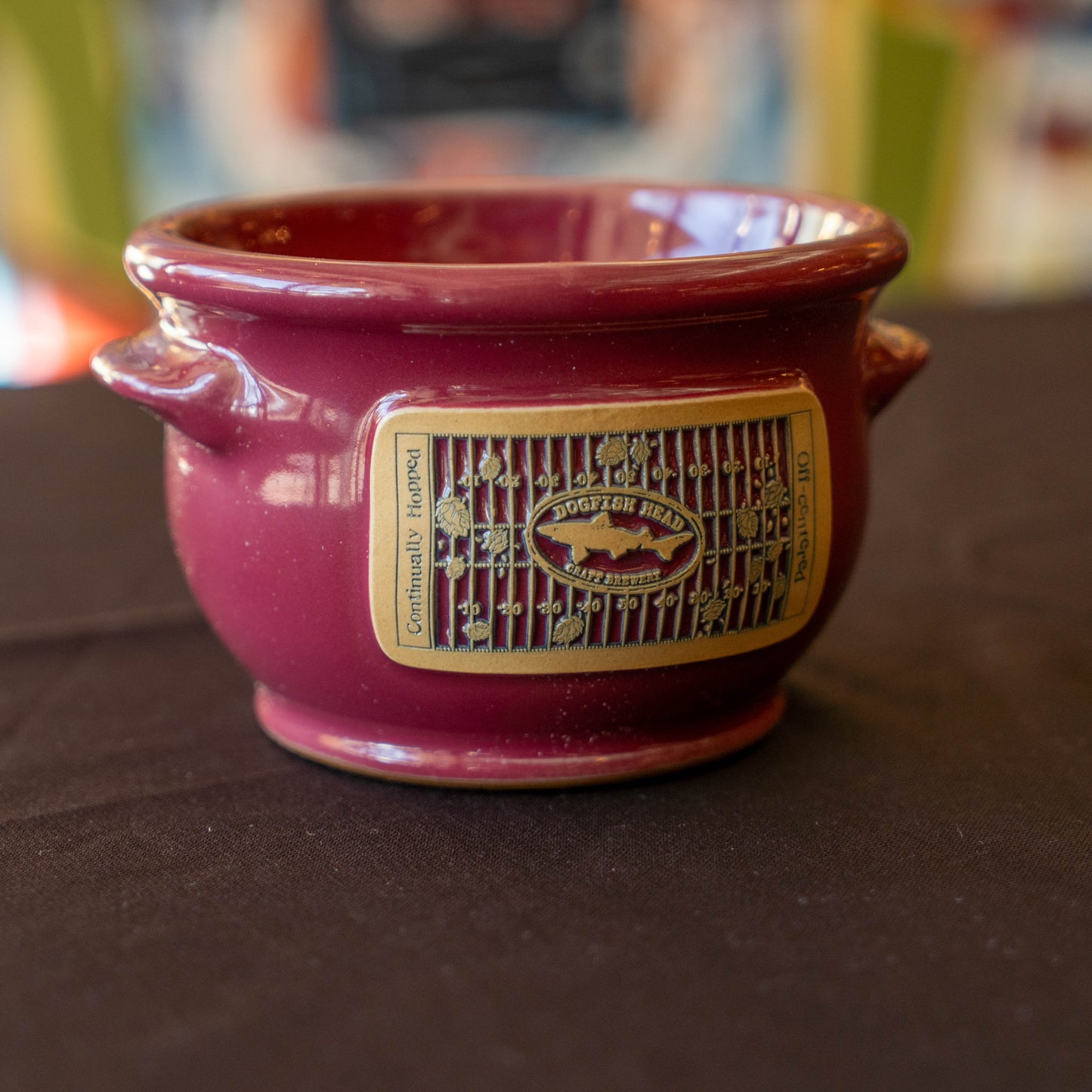 Red ceramic crock with a taupe label on a dark surface