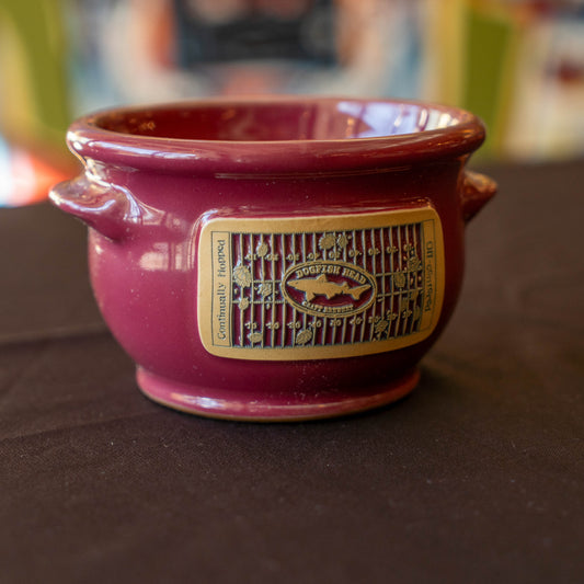 Red ceramic crock with a taupe label on a dark surface