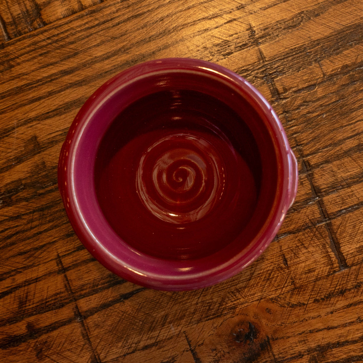 Red ceramic bowl with spiral design on a wooden surface