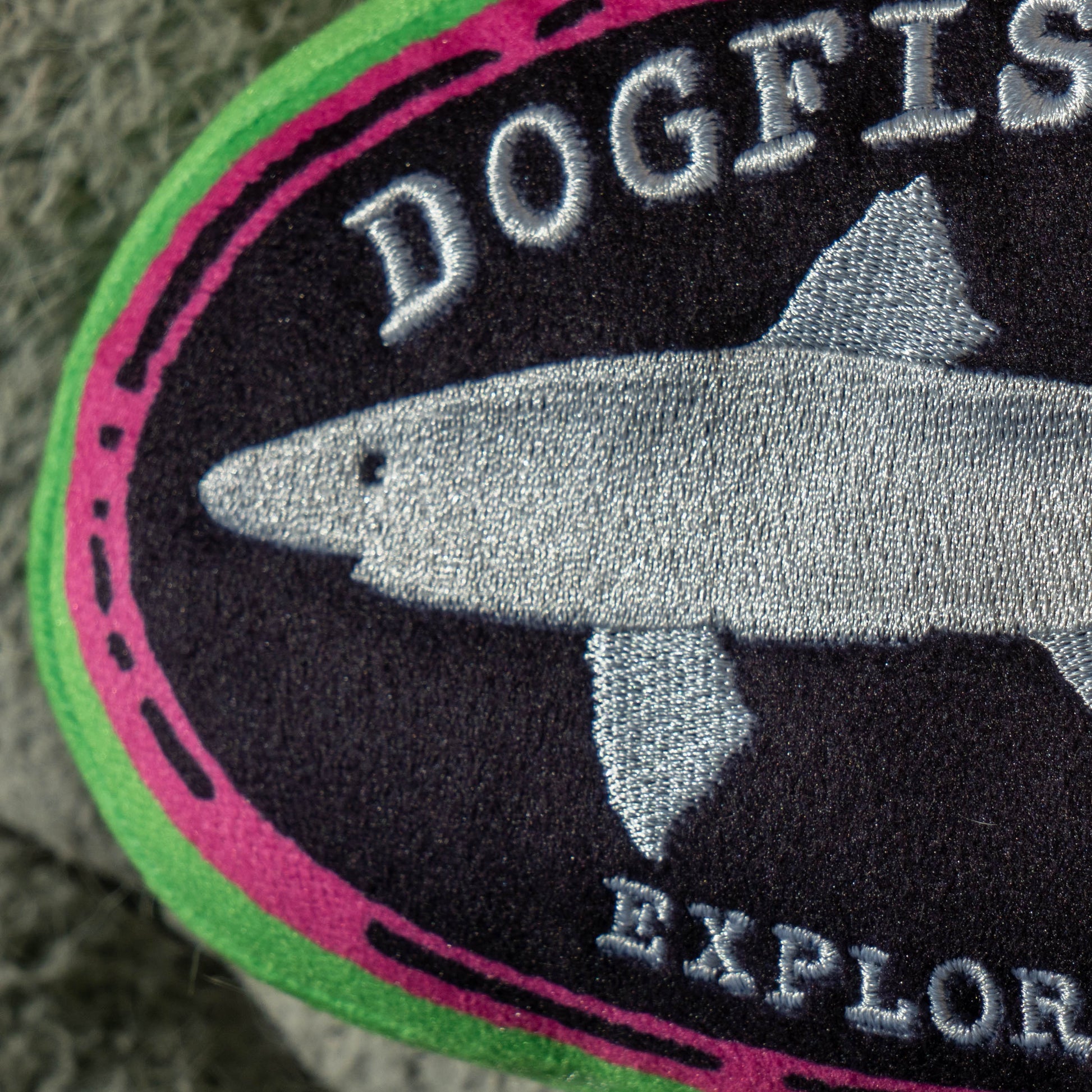 Close up of white embroidered shark on Dogfish Head Core logo plush dog toy
