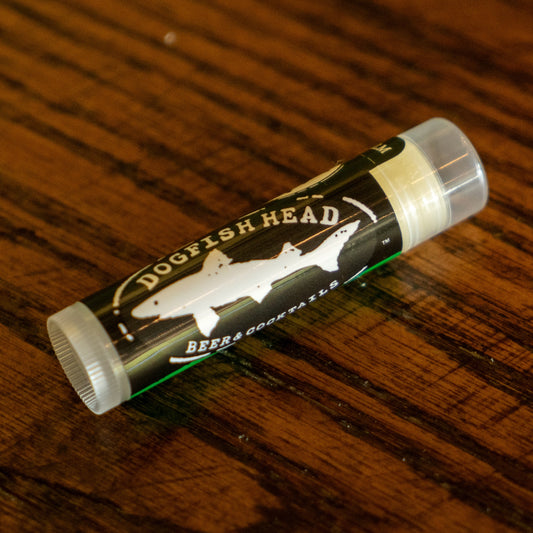 A tube of Eco Lips Inc Lip Balm sits on a wooden surface, its label suggesting a zesty and refreshing flavor from this organic lip balm.