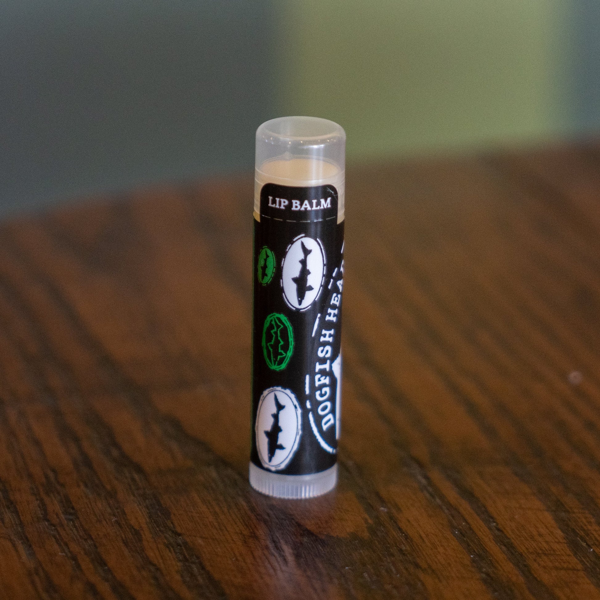 A tube of Eco Lips Inc Lip Balm stands upright on a wooden surface.