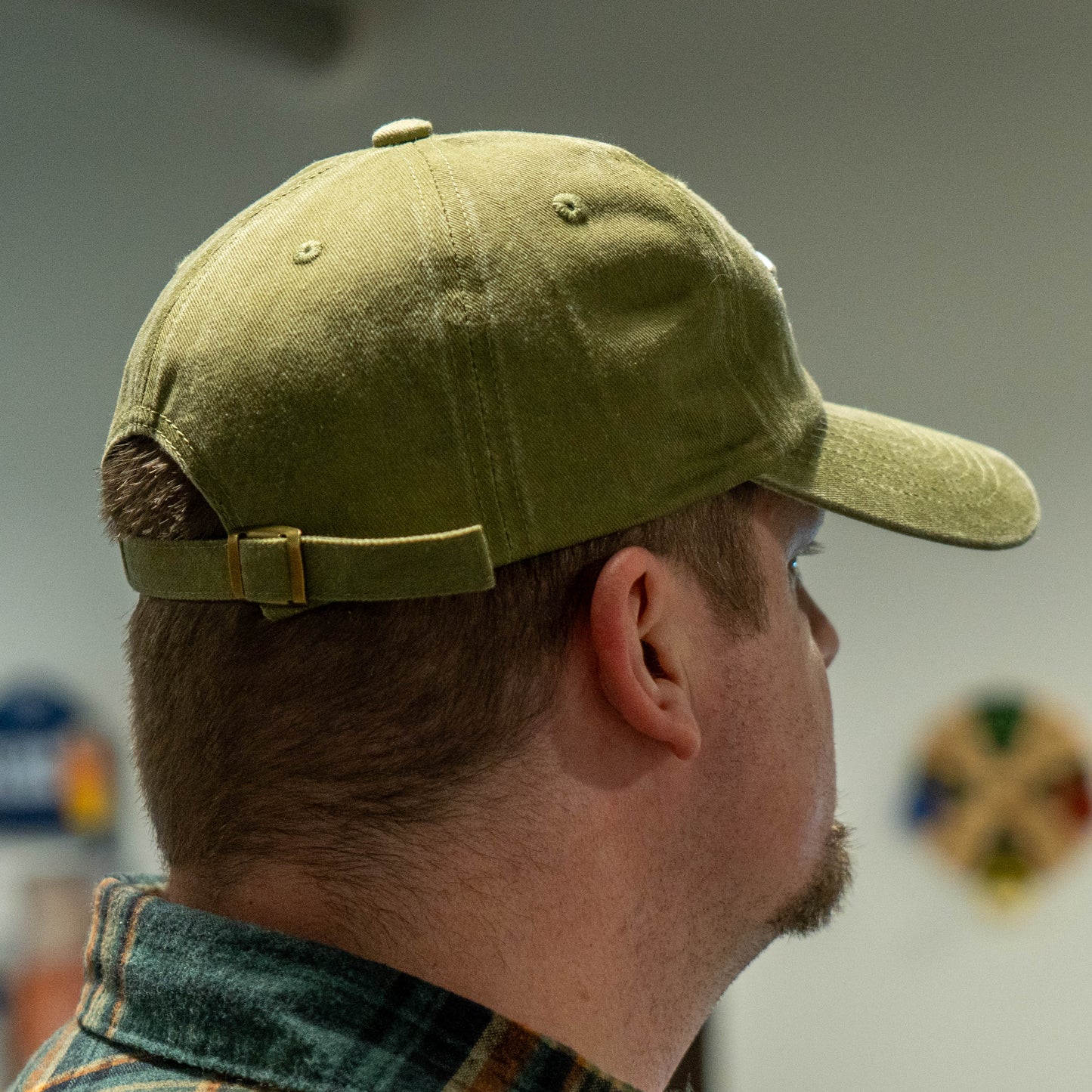 Back side view of a man wearing a Dogfish Head Olive simple logo dad hat 