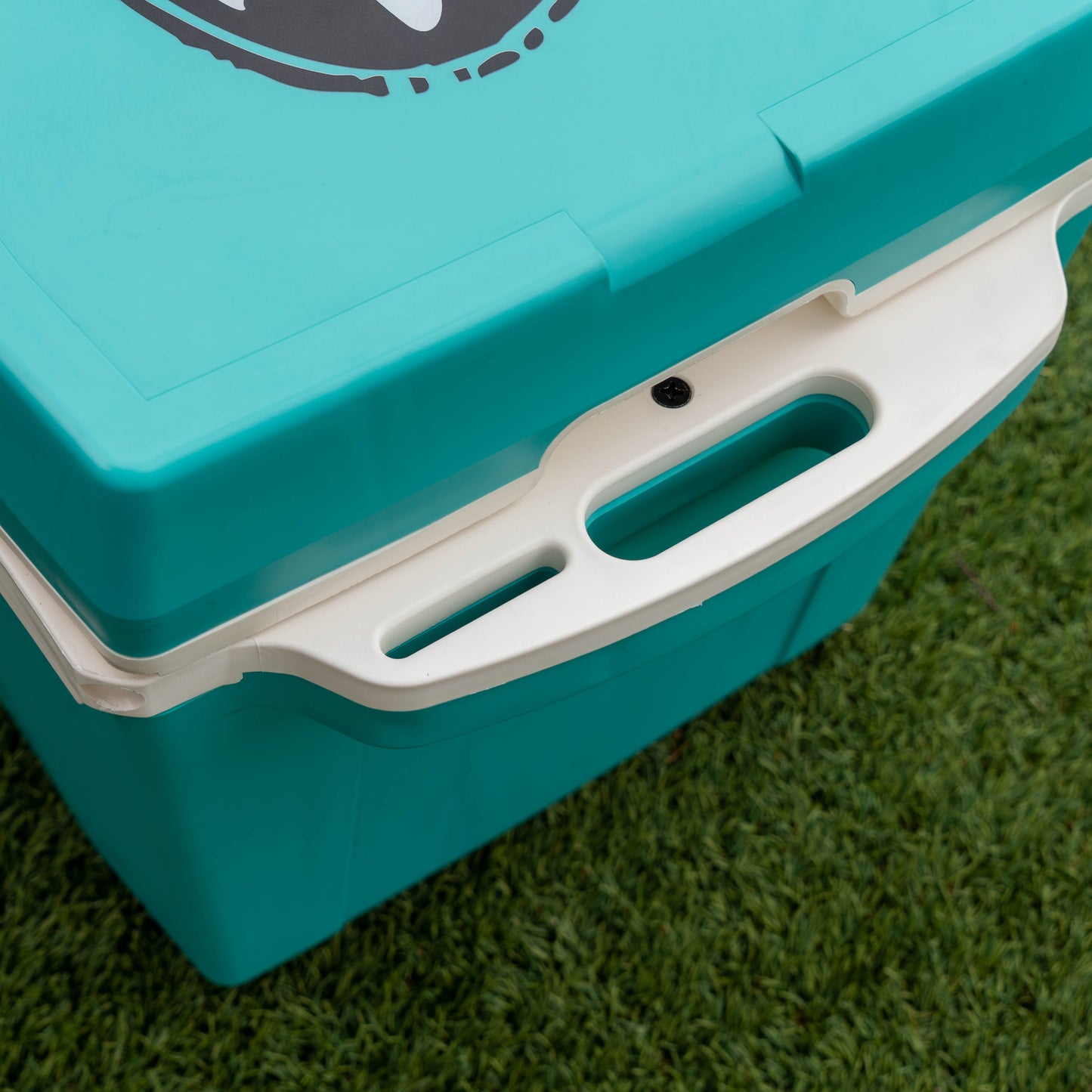 Turquoise cooler box with white handle on a grassy background