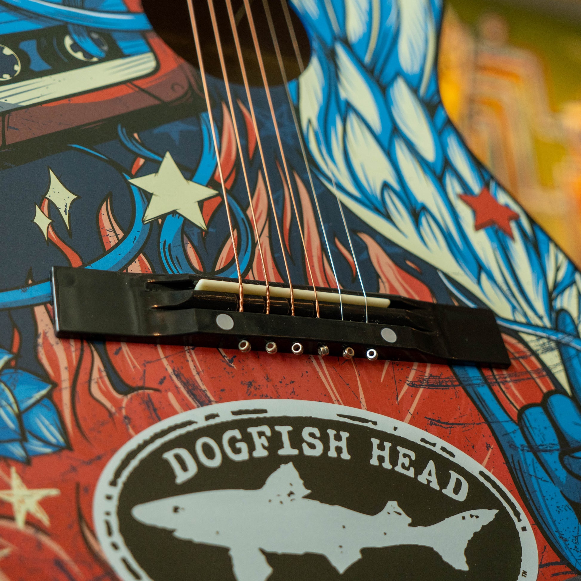 Close-up of a guitar with a colorful design and 'Dogfish Head' branding.
