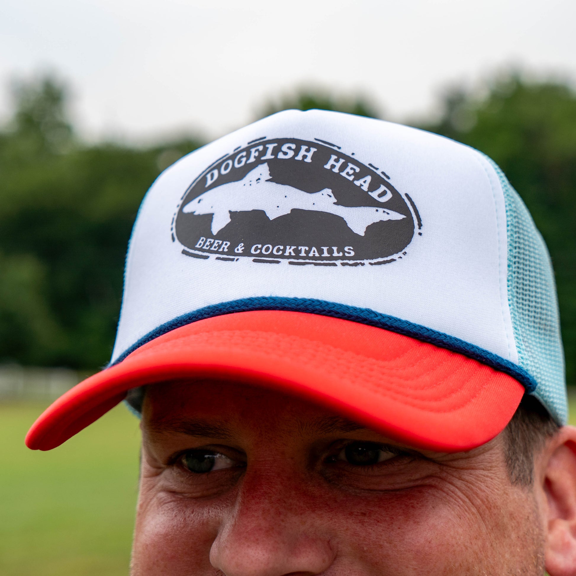 Person wearing a white and red cap with 'Dogfish Head' logo outdoors