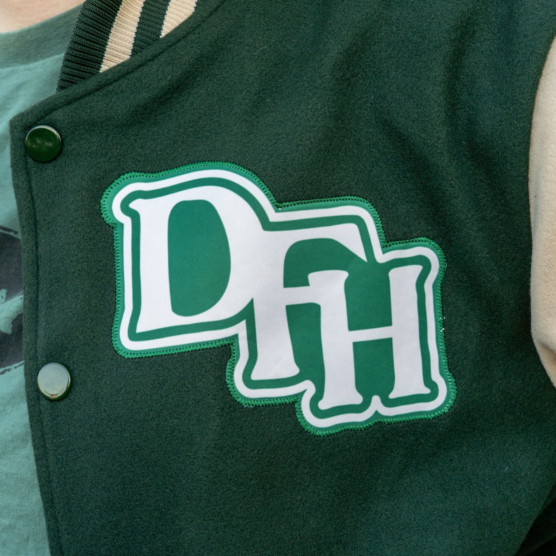 Green letterman jacket with 'DFH' logo on a person wearing a green shirt.